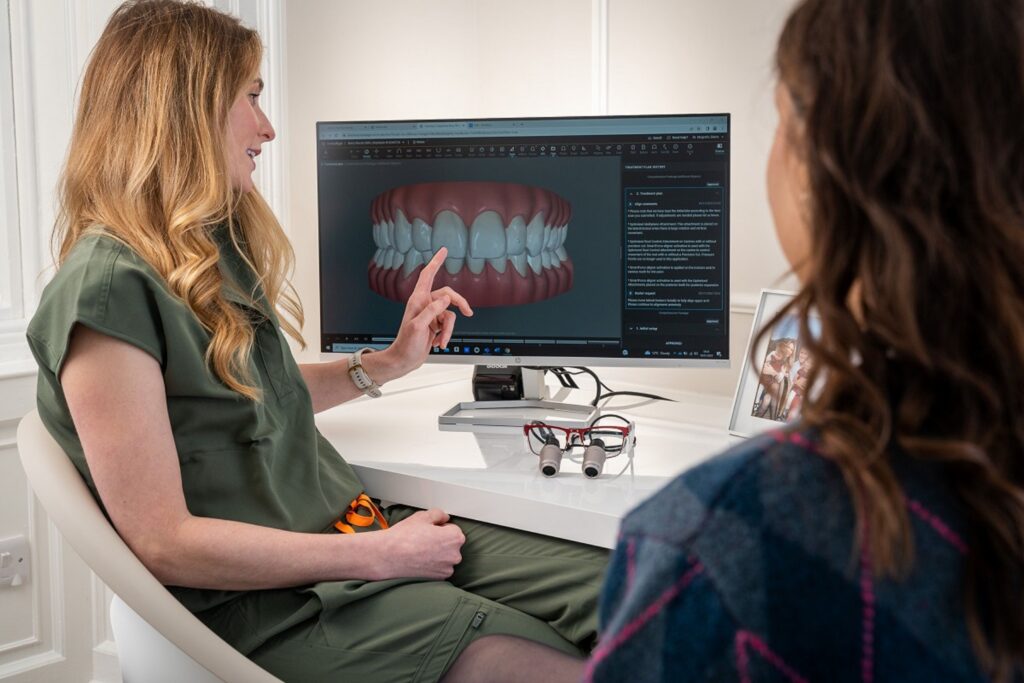 A dentist explains a 3D dental model to a patient during a consultation